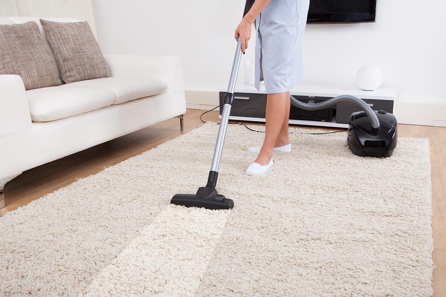 A man vacuuming an area carpet